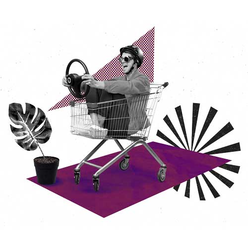 A man sitting in a shopping cart wearing a helmet and holding a steering wheel